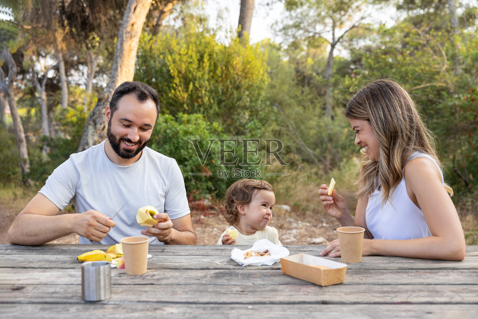 快乐的家庭在户外享受夏日野餐，品尝着水果。照片摄影图片