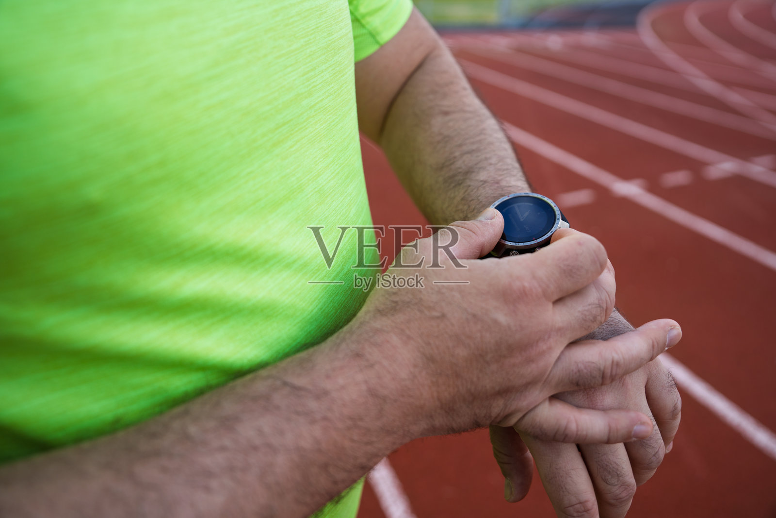 运动员在人造跑道上查看智能手表照片摄影图片