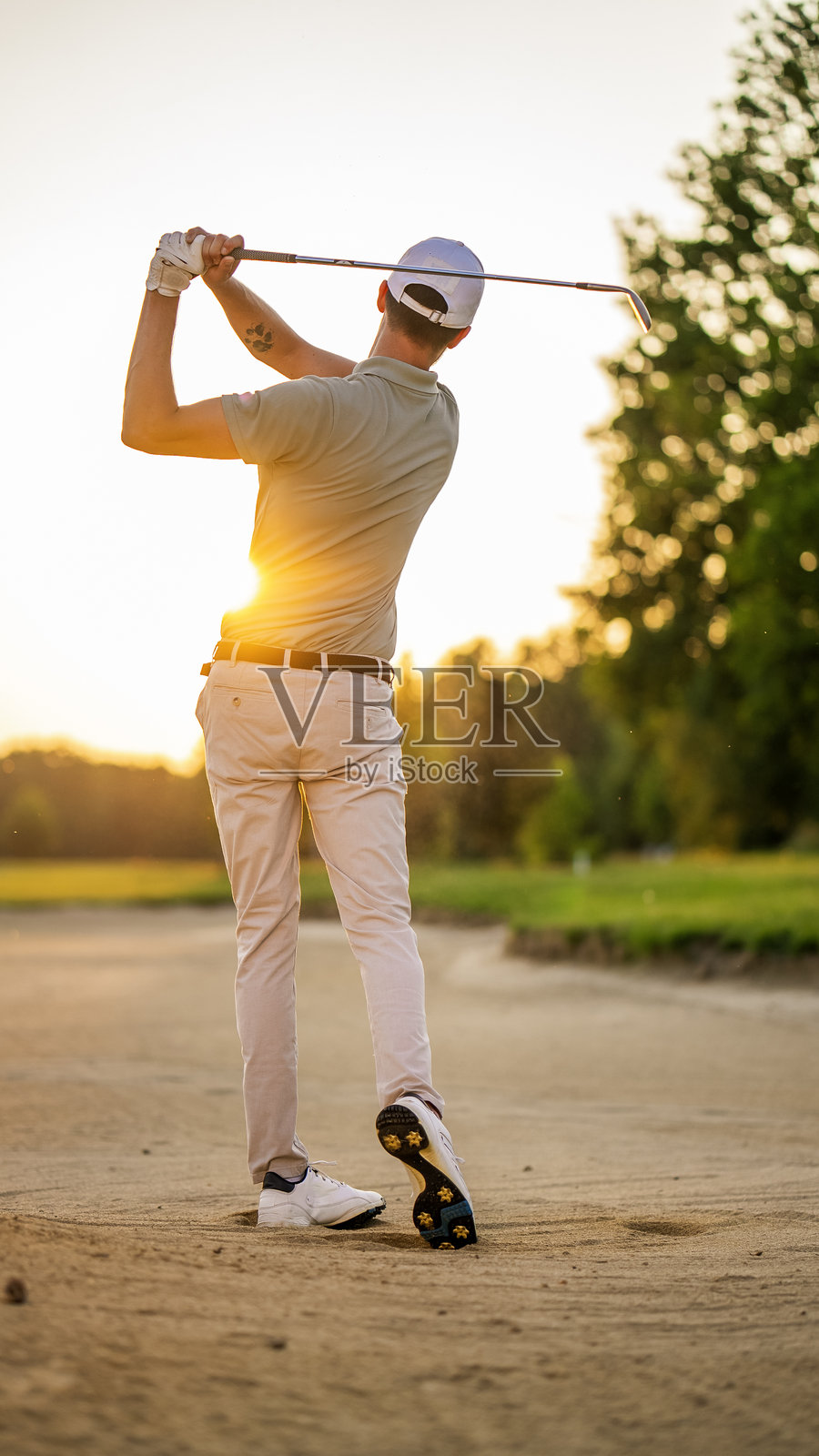中年高尔夫球手在黄昏时分沙坑中挥杆照片摄影图片