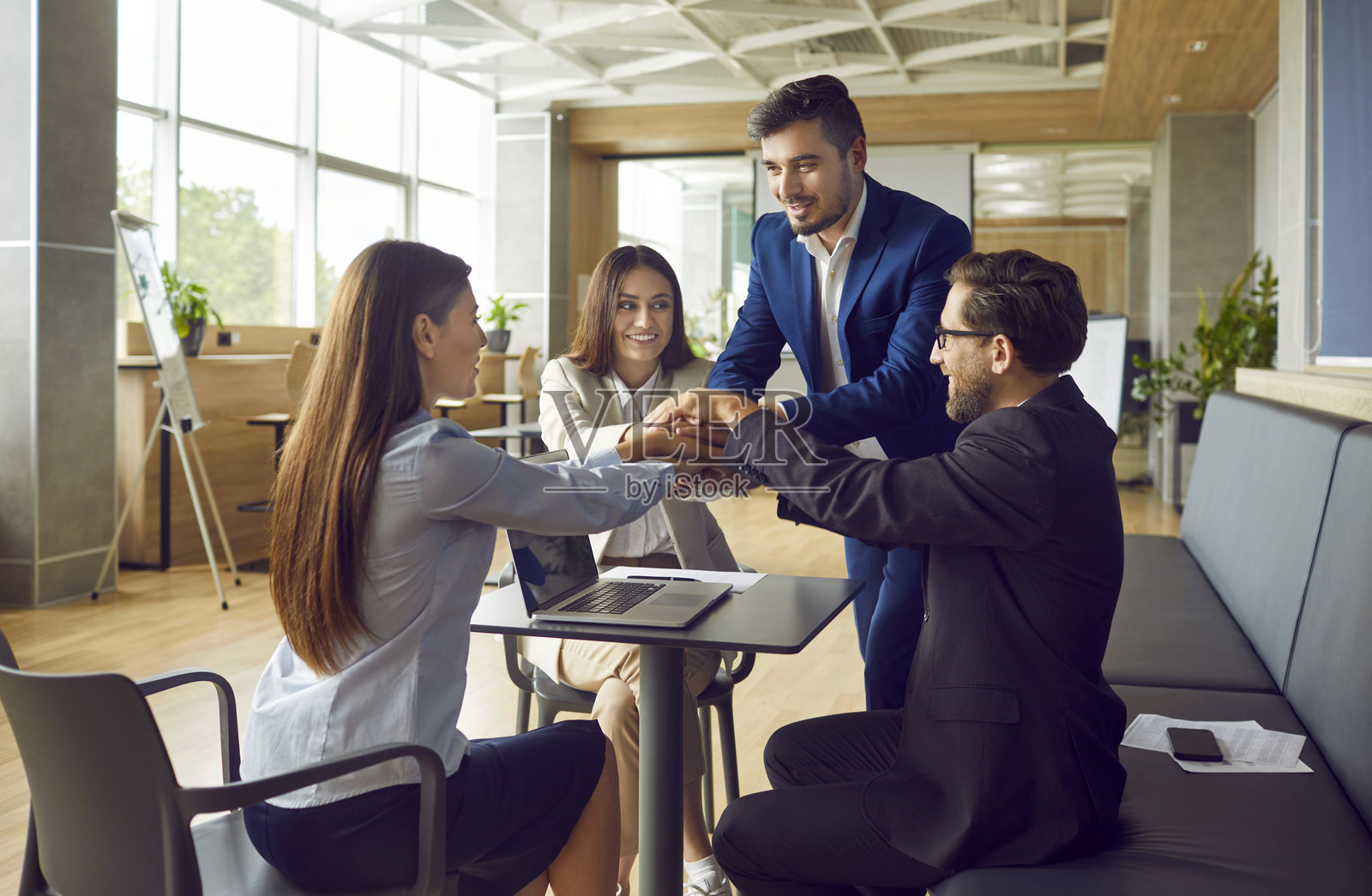 办公室会议上，一群快乐的商界人士在办公桌前叠手照片摄影图片