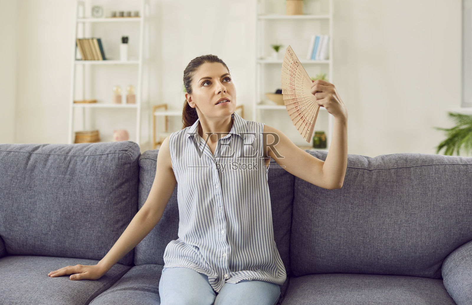 焦虑疲惫的女性在家中因夏季高温而使用风扇纳凉照片摄影图片
