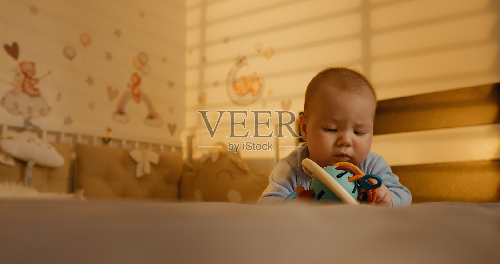 男婴一边用手指按摩牙龈，一边用眼睛跟着某人看。照片摄影图片