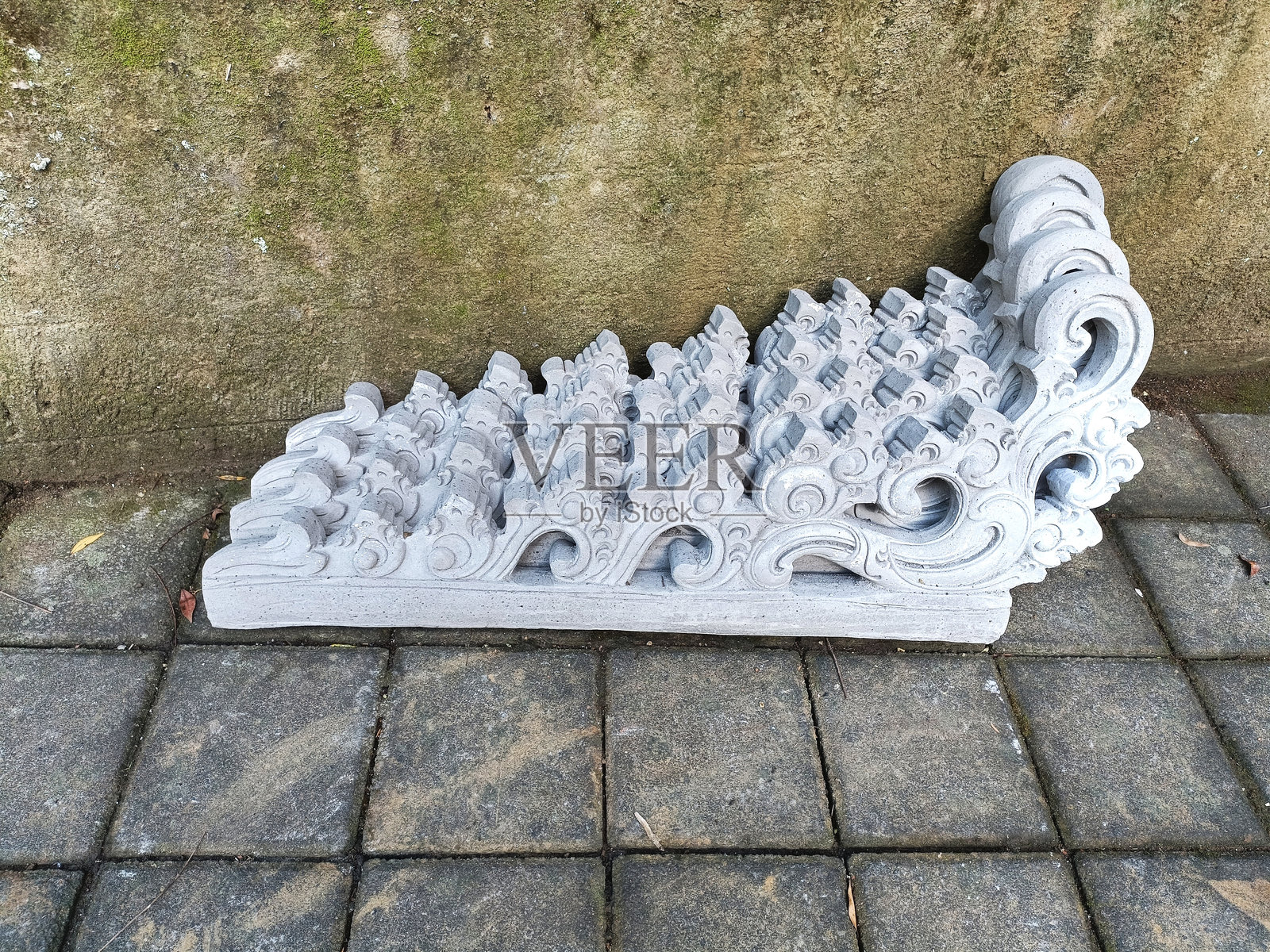 靠在脏石膏墙上的巴厘岛屋顶水泥装饰品照片摄影图片