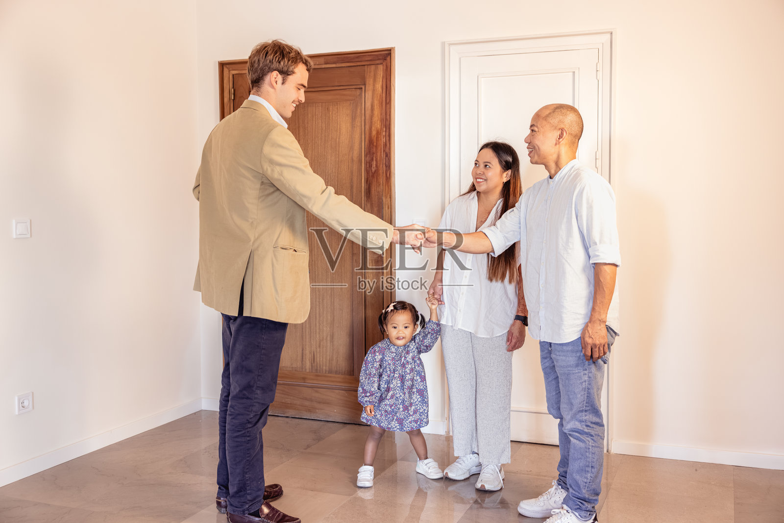 房产经纪人与一家人（包括孩子）握手，他们正在购买或租赁房屋照片摄影图片