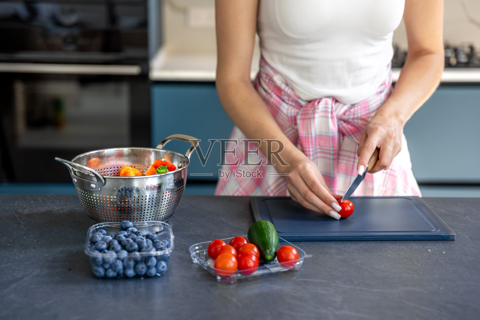 女人在厨房里切番茄，制作新鲜沙拉。简单的沙拉。照片摄影图片