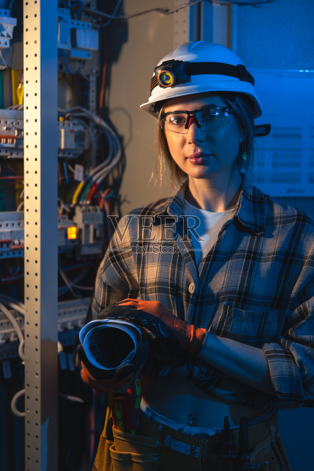 女电工在夜间控制室手持蓝图，专业肖像。照片摄影图片