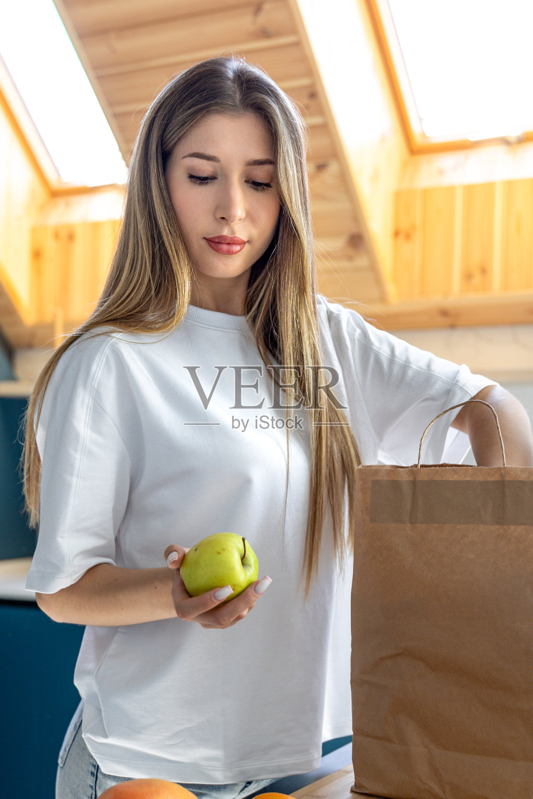 女人在厨房的环保袋里拿了一个苹果。新鲜的选择。照片摄影图片