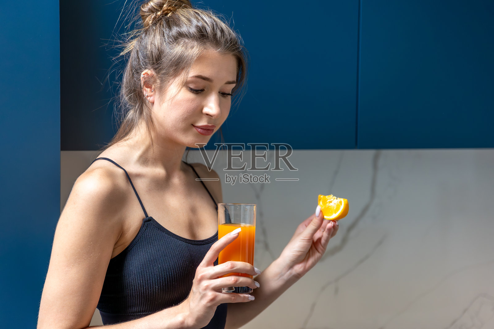 运动后，女士喝橙汁补充维生素。照片摄影图片