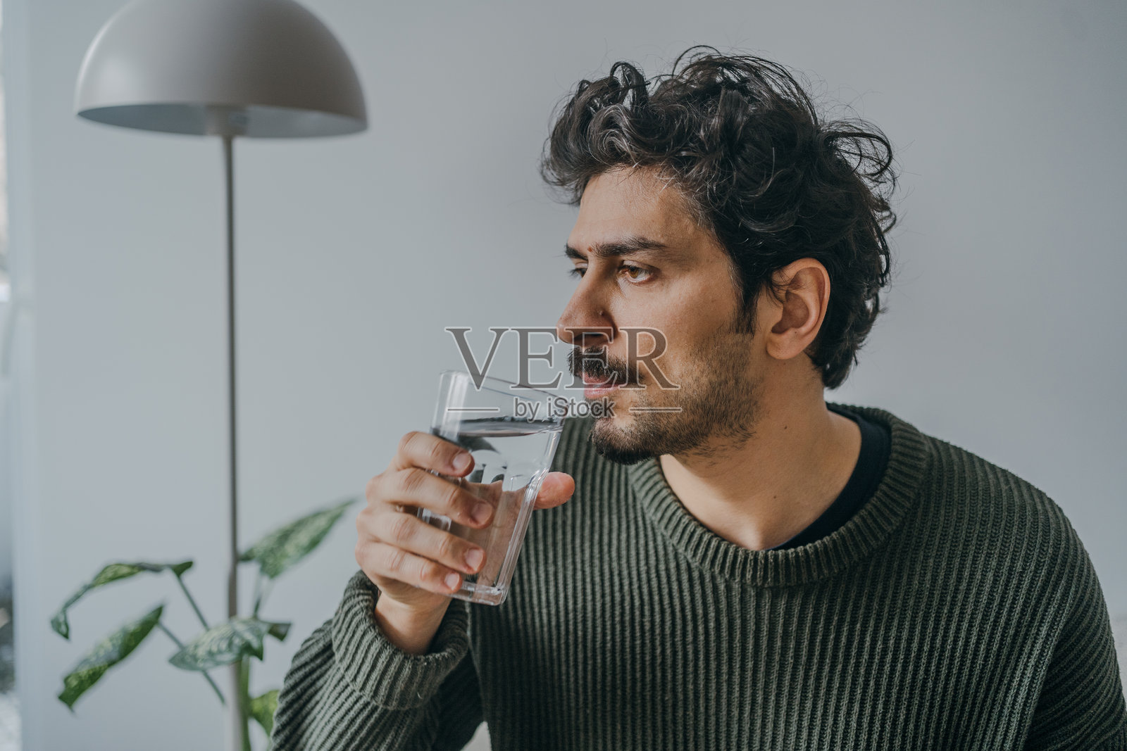 帅气的阿拉伯男子正在饮水，强调补水。照片摄影图片