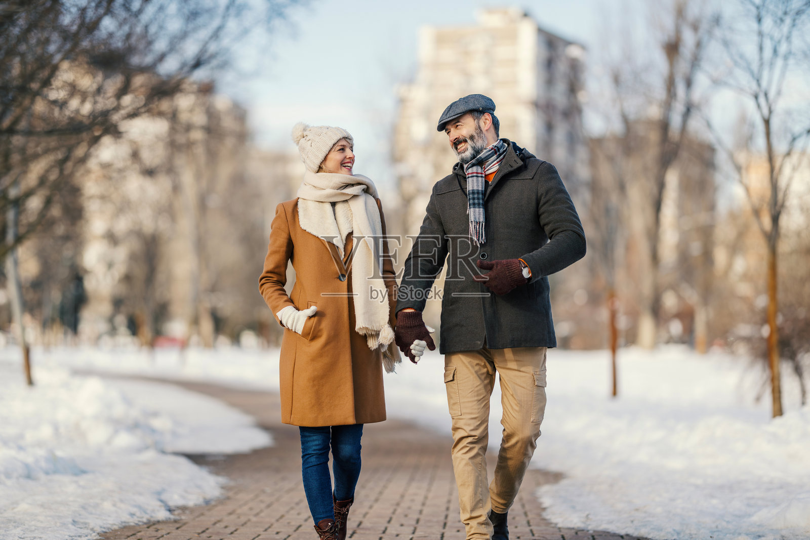 一对幸福的情侣手牵手走在雪地公园里照片摄影图片