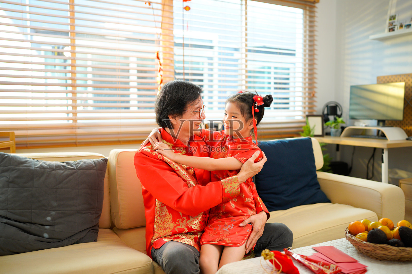 一位年长的中国爷爷正和他的小孙女在客厅的沙发上放松，共享春节家庭时光。照片摄影图片