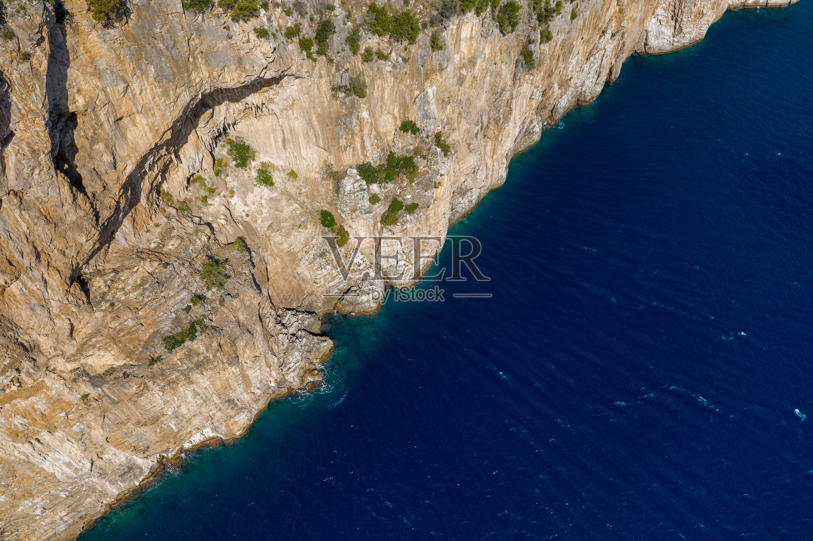 崎岖悬崖与深邃蓝海的空中俯瞰视角照片摄影图片