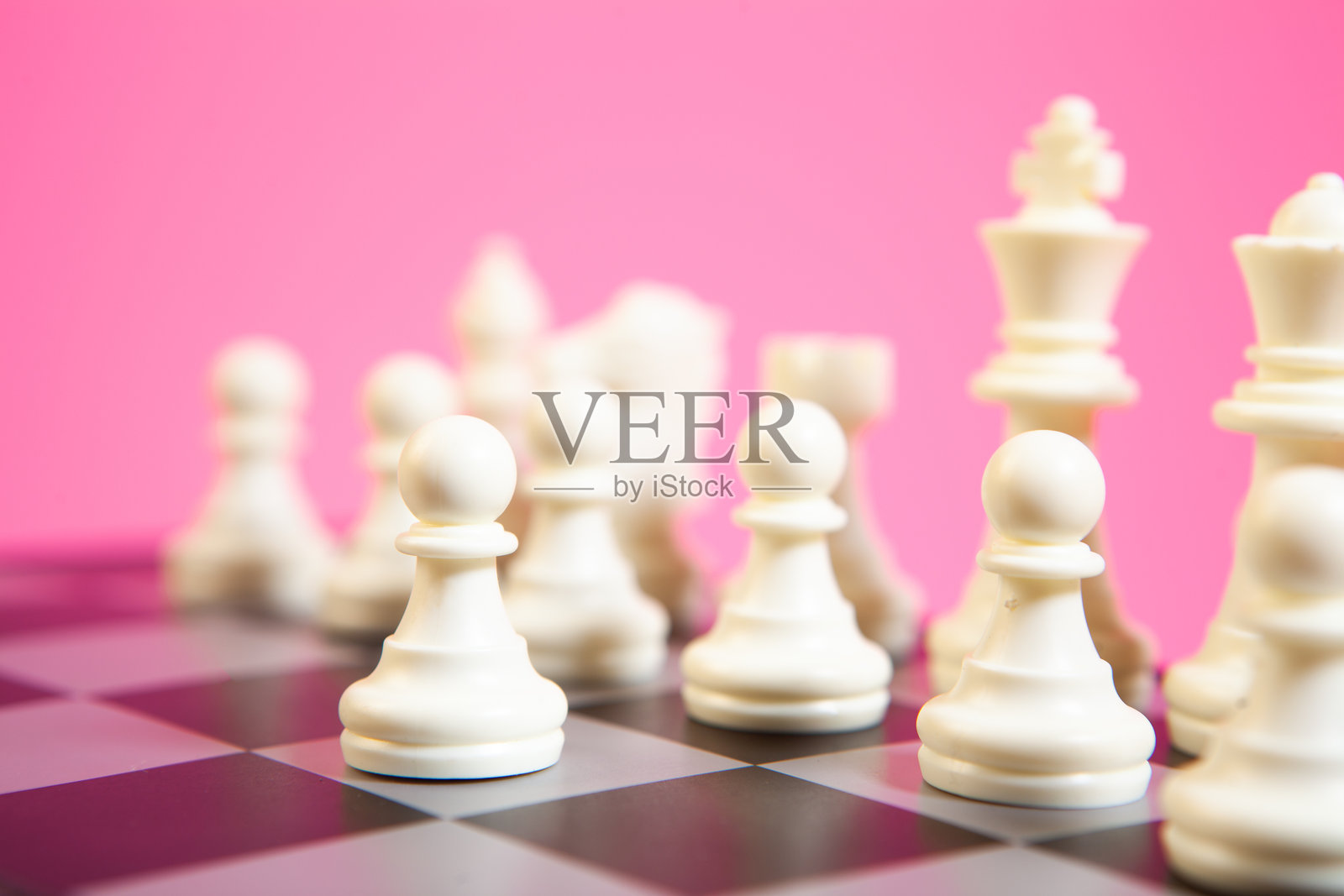 粉色背景的国际象棋棋盘上的棋子，焦点在部分棋子。照片摄影图片