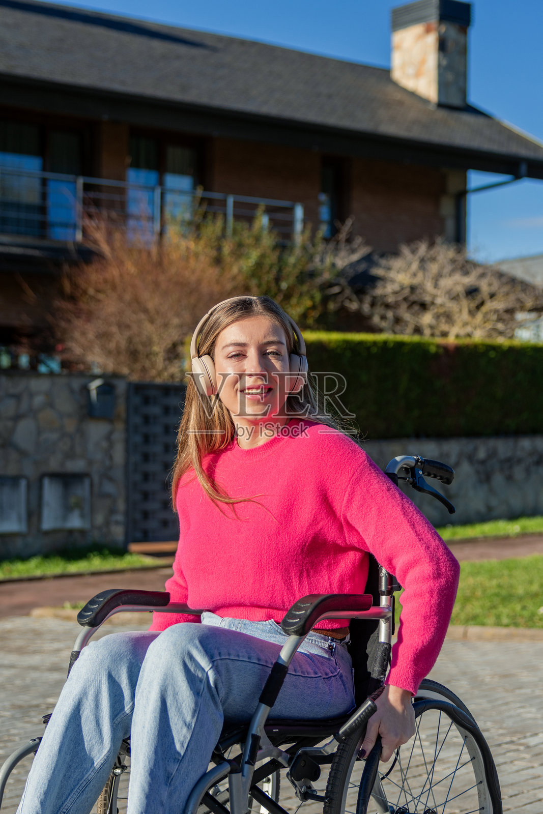 坐轮椅的年轻女子戴着耳机在户外微笑照片摄影图片