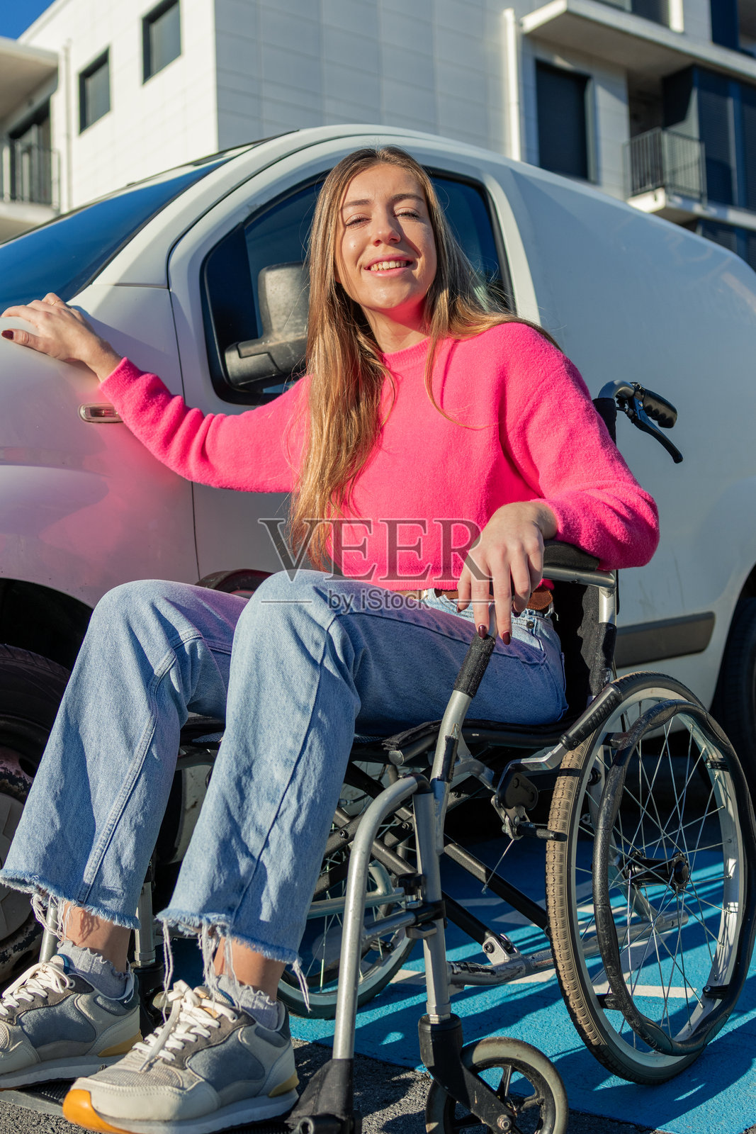 坐轮椅的年轻女子在无障碍货车旁微笑，竖幅构图照片摄影图片