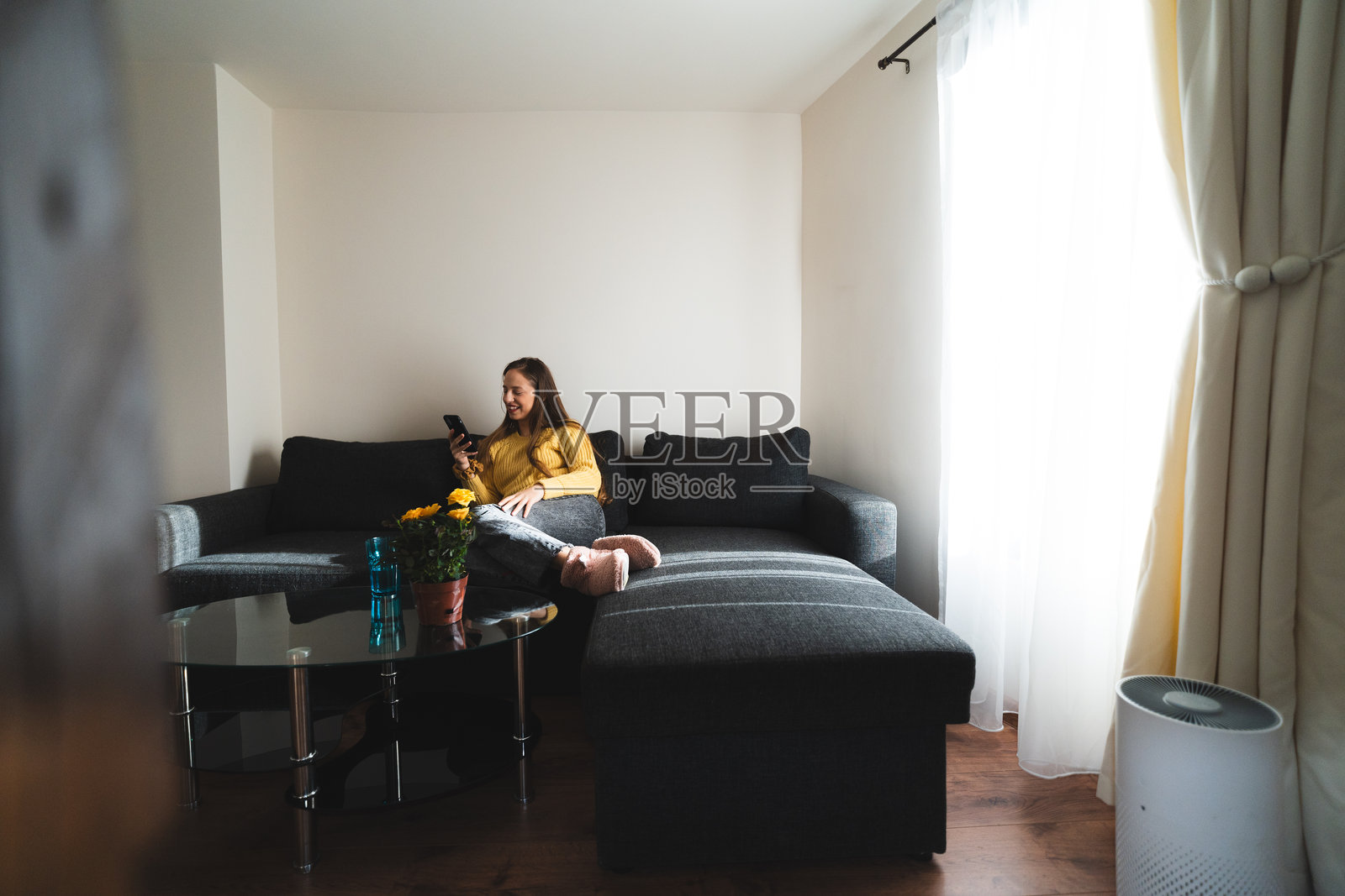 女人在家中放松玩手机，享受清新空气的休闲生活瞬间照片摄影图片