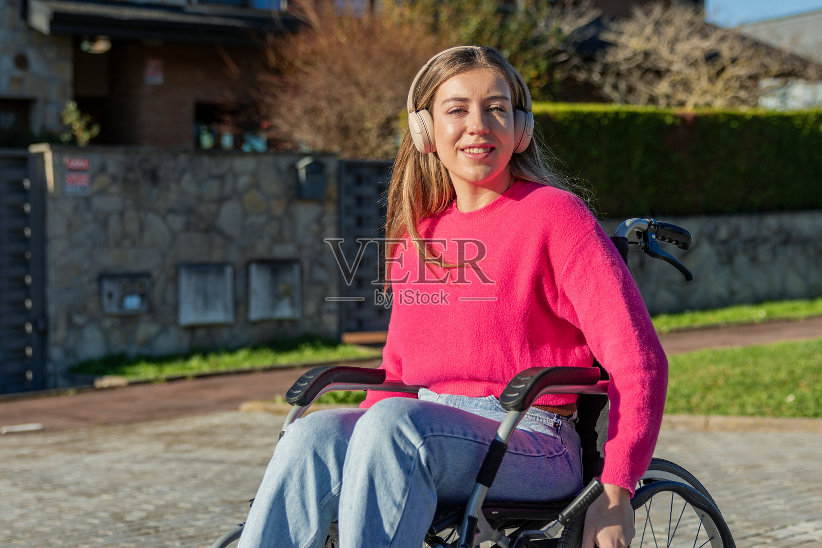 年轻女子坐在轮椅上，戴着耳机在户外享受音乐照片摄影图片