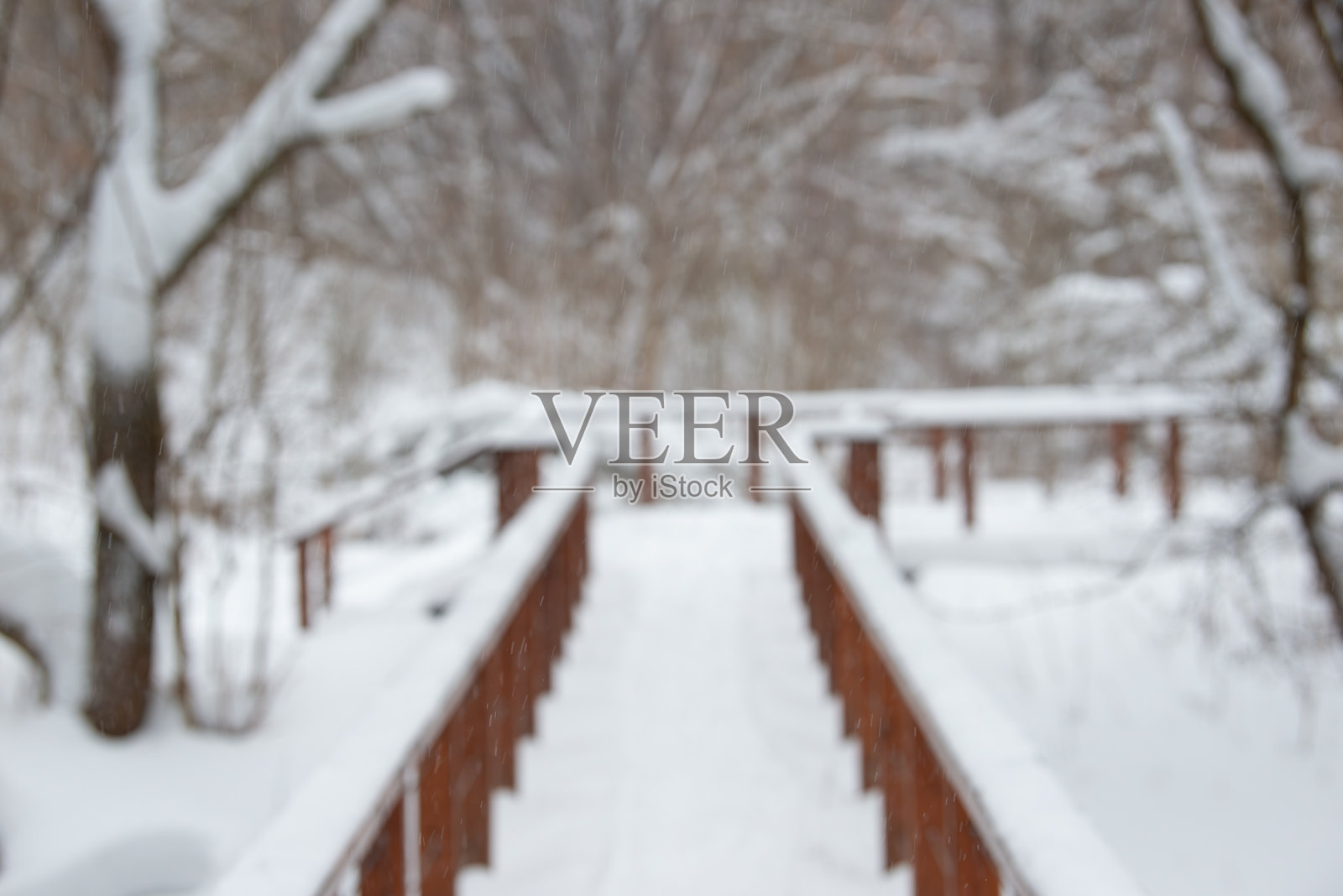 模糊的冬季景观。冬季森林中的木桥。照片摄影图片