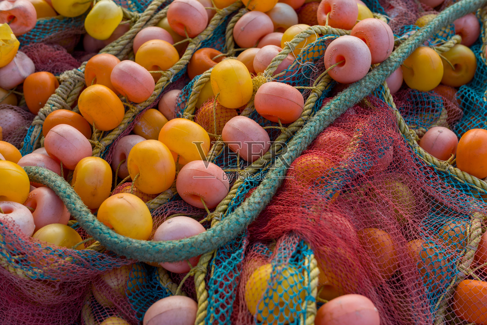 鲜艳的橙色和粉色漂浮在色彩斑斓的渔网上照片摄影图片