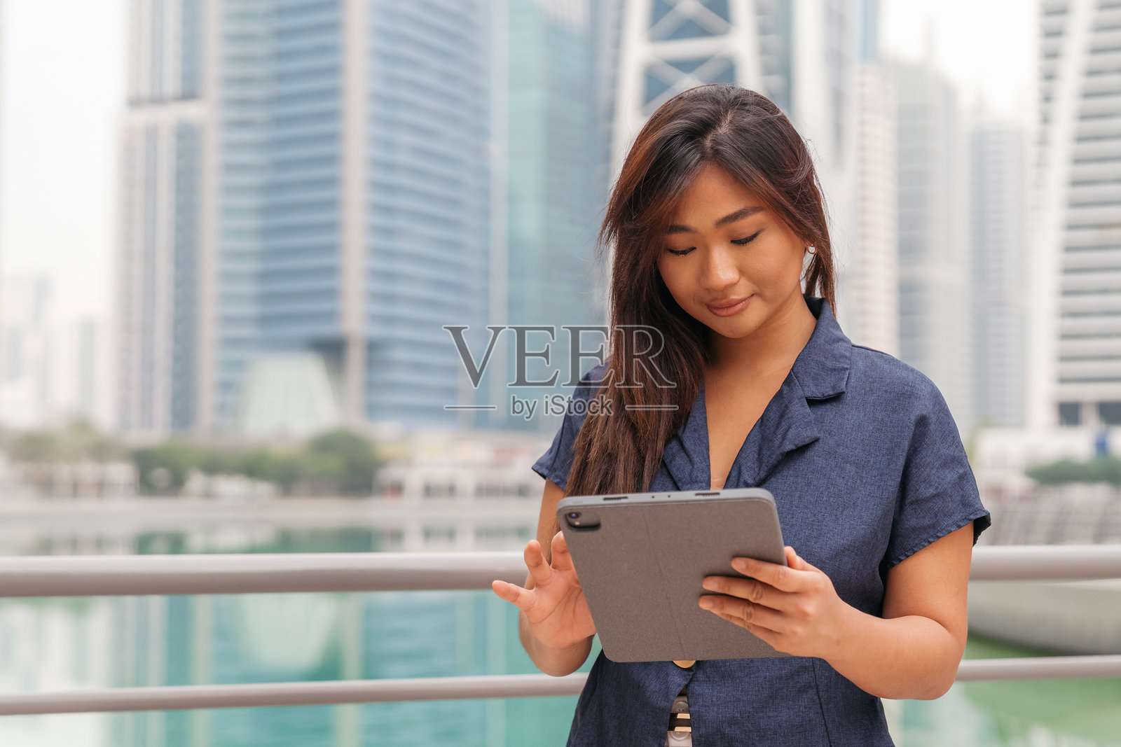 亚洲职业女性在现代都市背景下使用平板电脑工作照片摄影图片