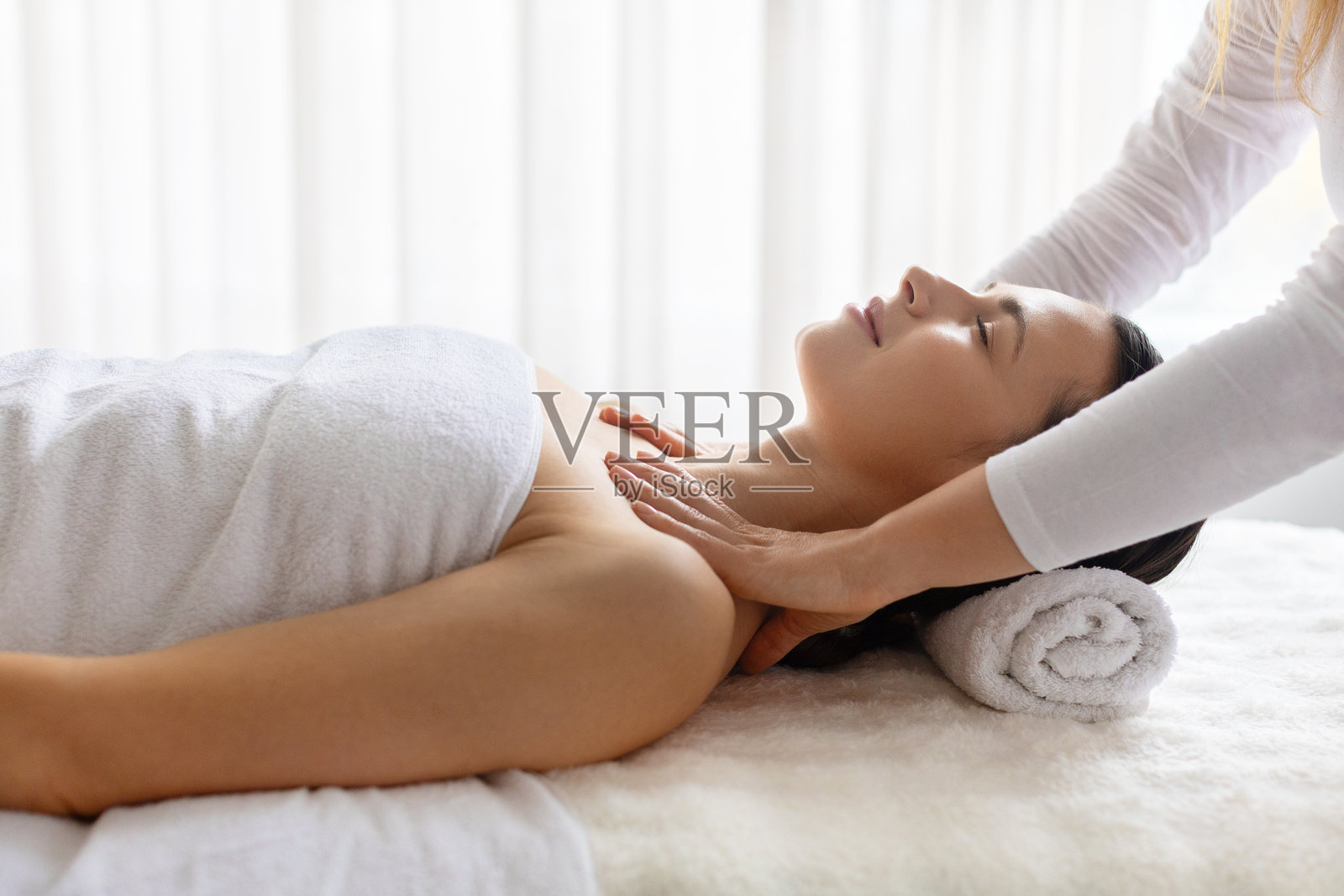 年轻美丽的女子正在接受上半身水疗护理，理疗师的手放在她的肩膀上照片摄影图片