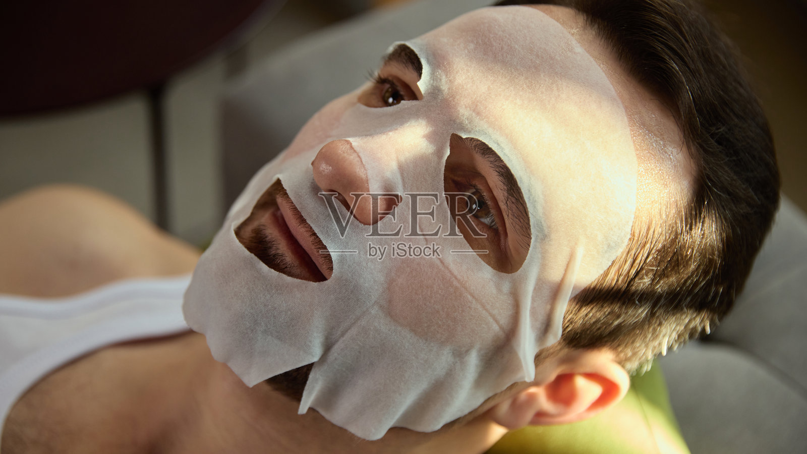 男子在柔和的日光下敷着面膜放松照片摄影图片