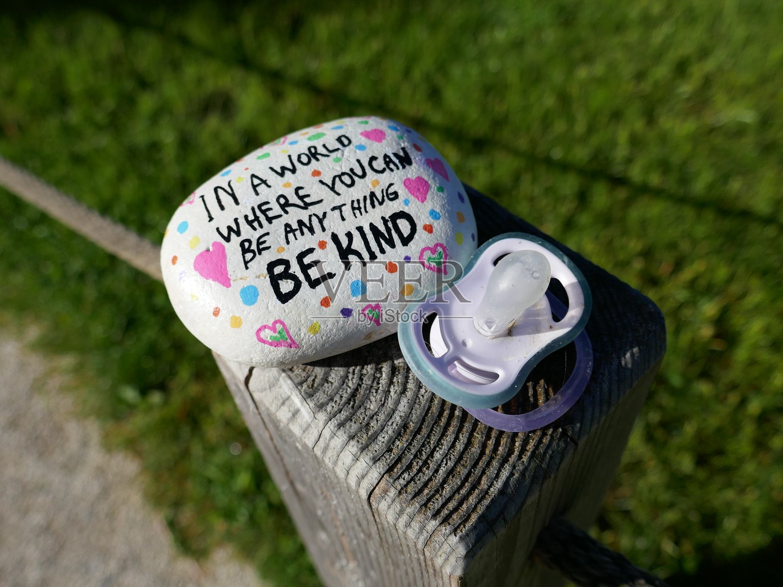 婴儿奶嘴和友善关爱石头放在栅栏柱上照片摄影图片