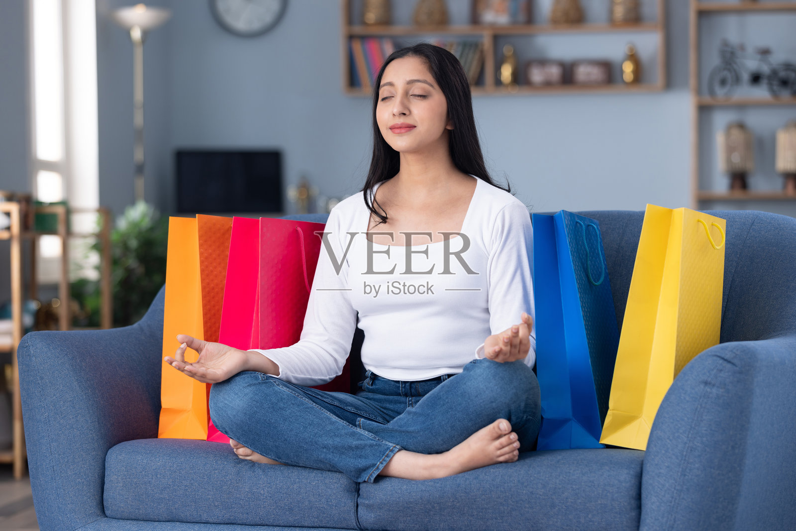 漂亮的年轻女孩提着购物袋坐在家里的沙发上照片摄影图片