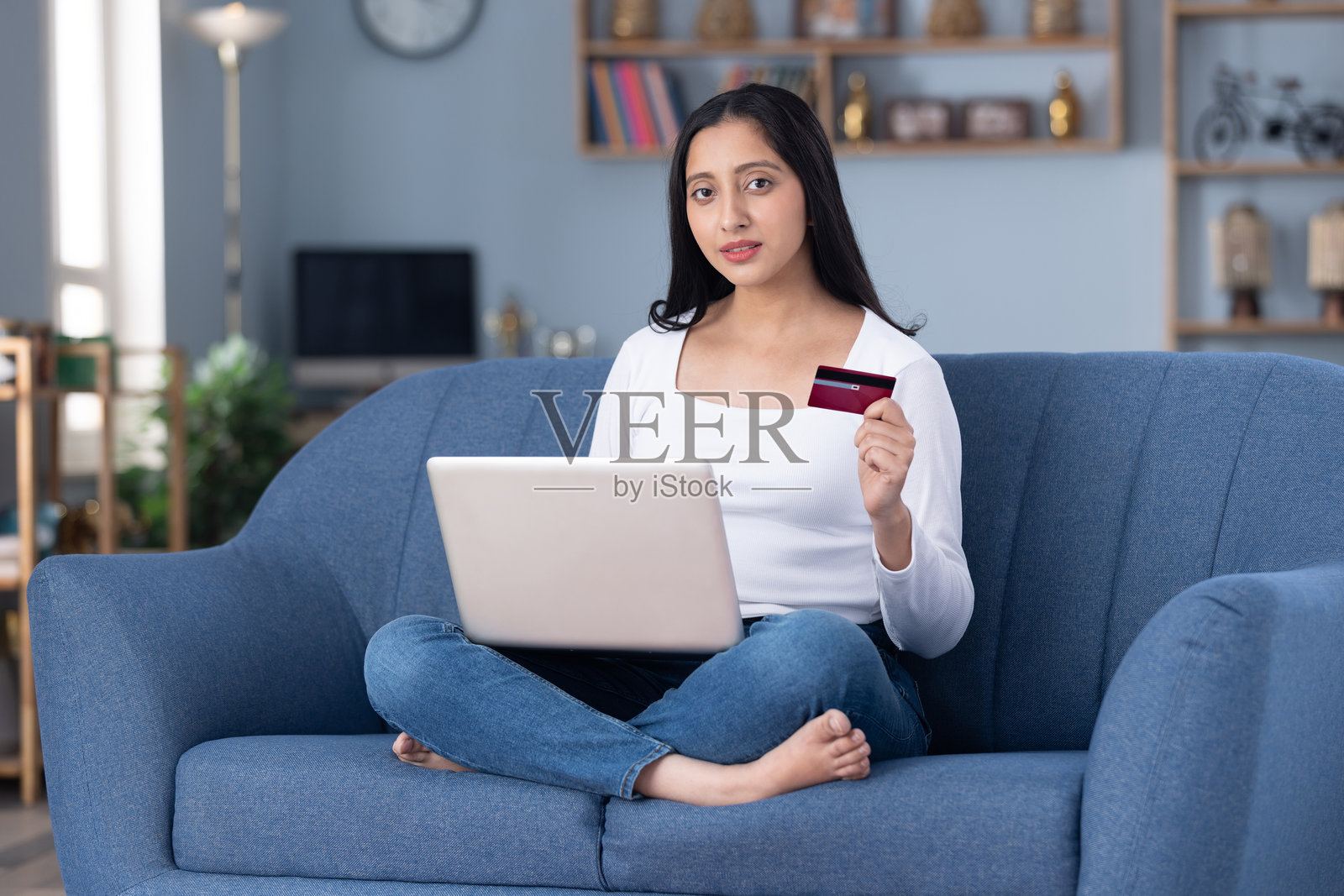 身穿现代服装的漂亮年轻女孩在家里的沙发上在线购物的图片素材照片摄影图片