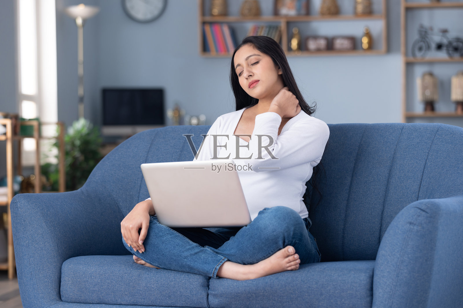 身穿时尚服装的漂亮年轻女孩在家中沙发上使用笔记本电脑的库存照片照片摄影图片