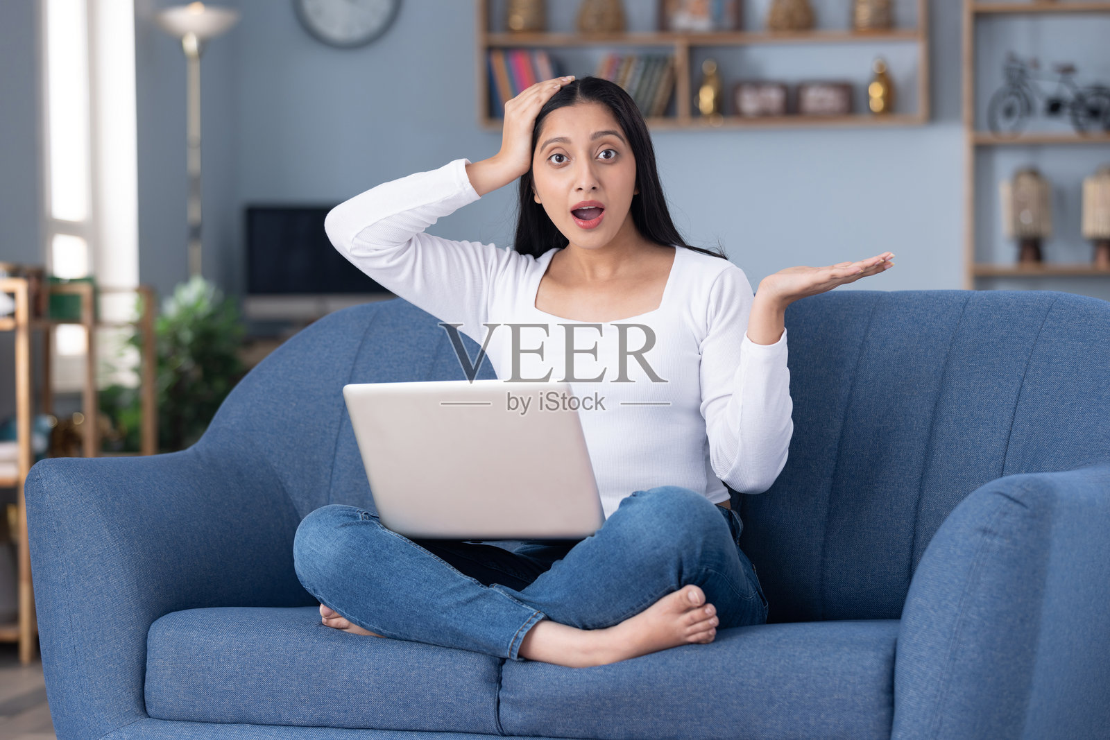 身穿现代服装的漂亮年轻女孩在家中坐在沙发上使用笔记本电脑的图片素材照片摄影图片