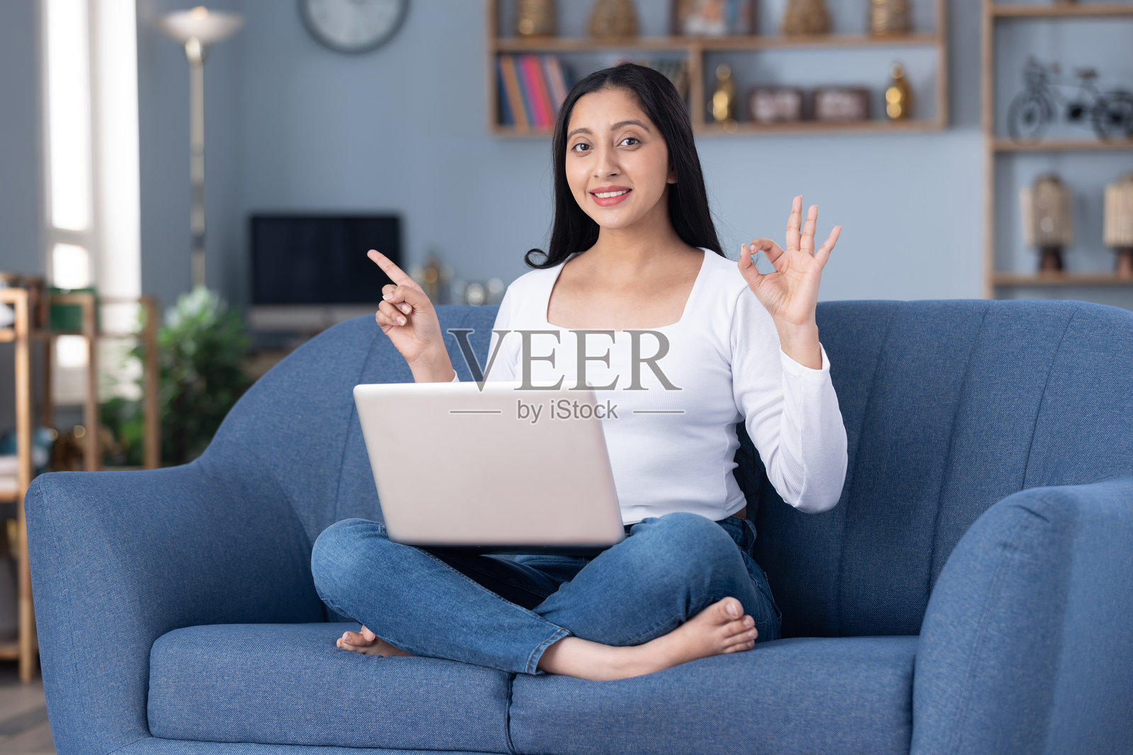 身穿时尚服装的漂亮年轻女孩在家中沙发上使用笔记本电脑的图片照片摄影图片