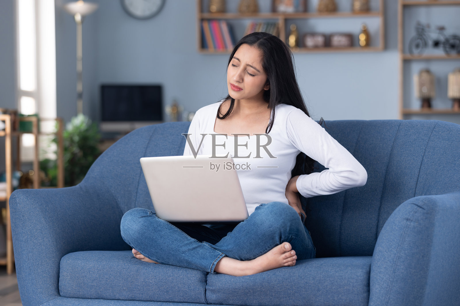 身穿时尚服装的年轻漂亮女孩在家中沙发上使用笔记本电脑的居家照片照片摄影图片