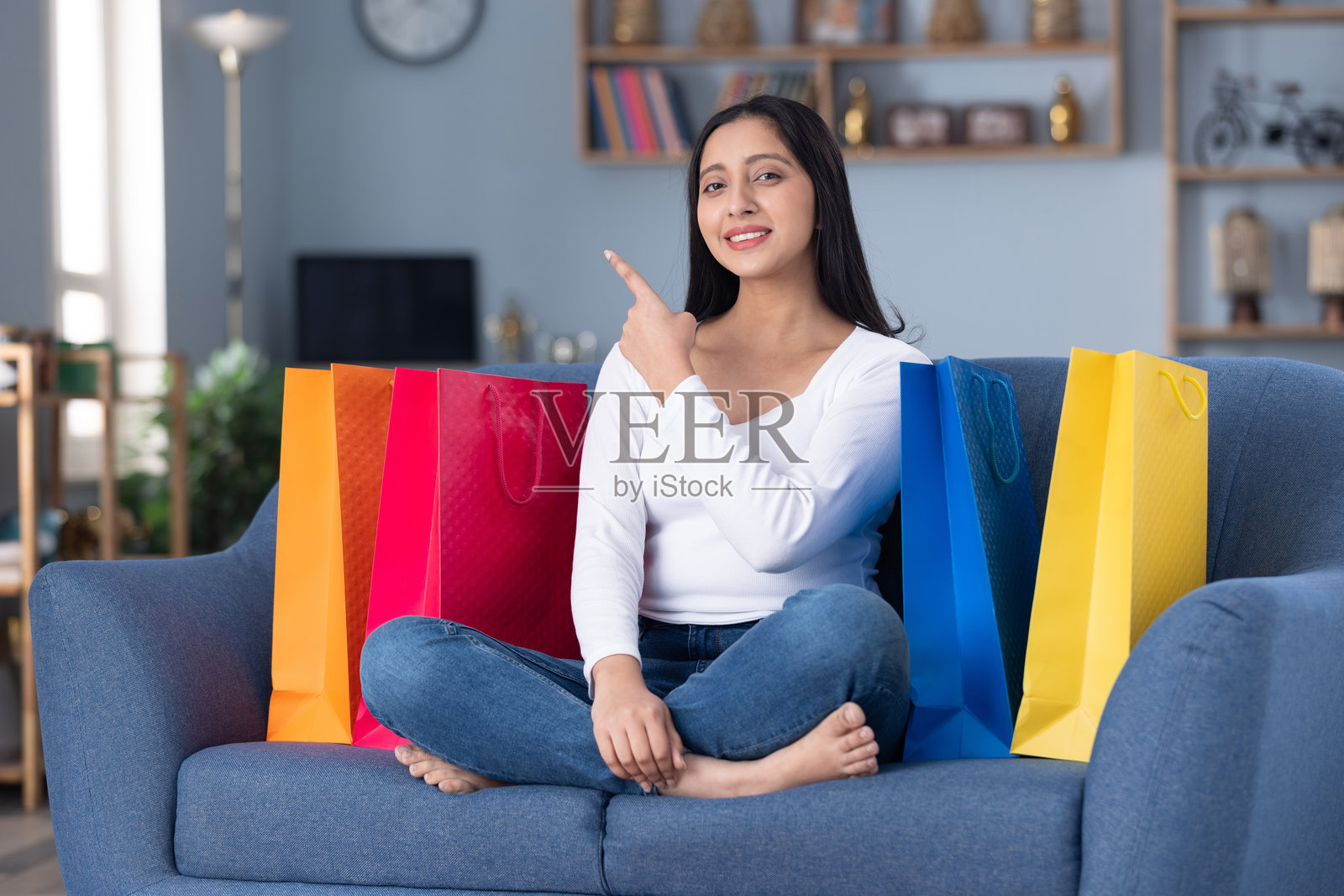 一位漂亮的年轻女孩提着购物袋坐在家中沙发上的照片素材照片摄影图片