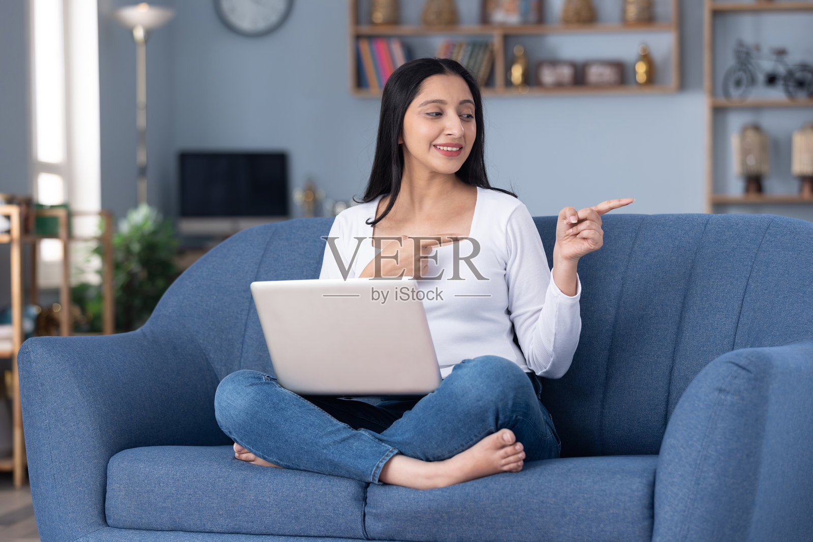 穿着时尚的年轻漂亮女孩在家坐在沙发上使用笔记本电脑的图片照片摄影图片