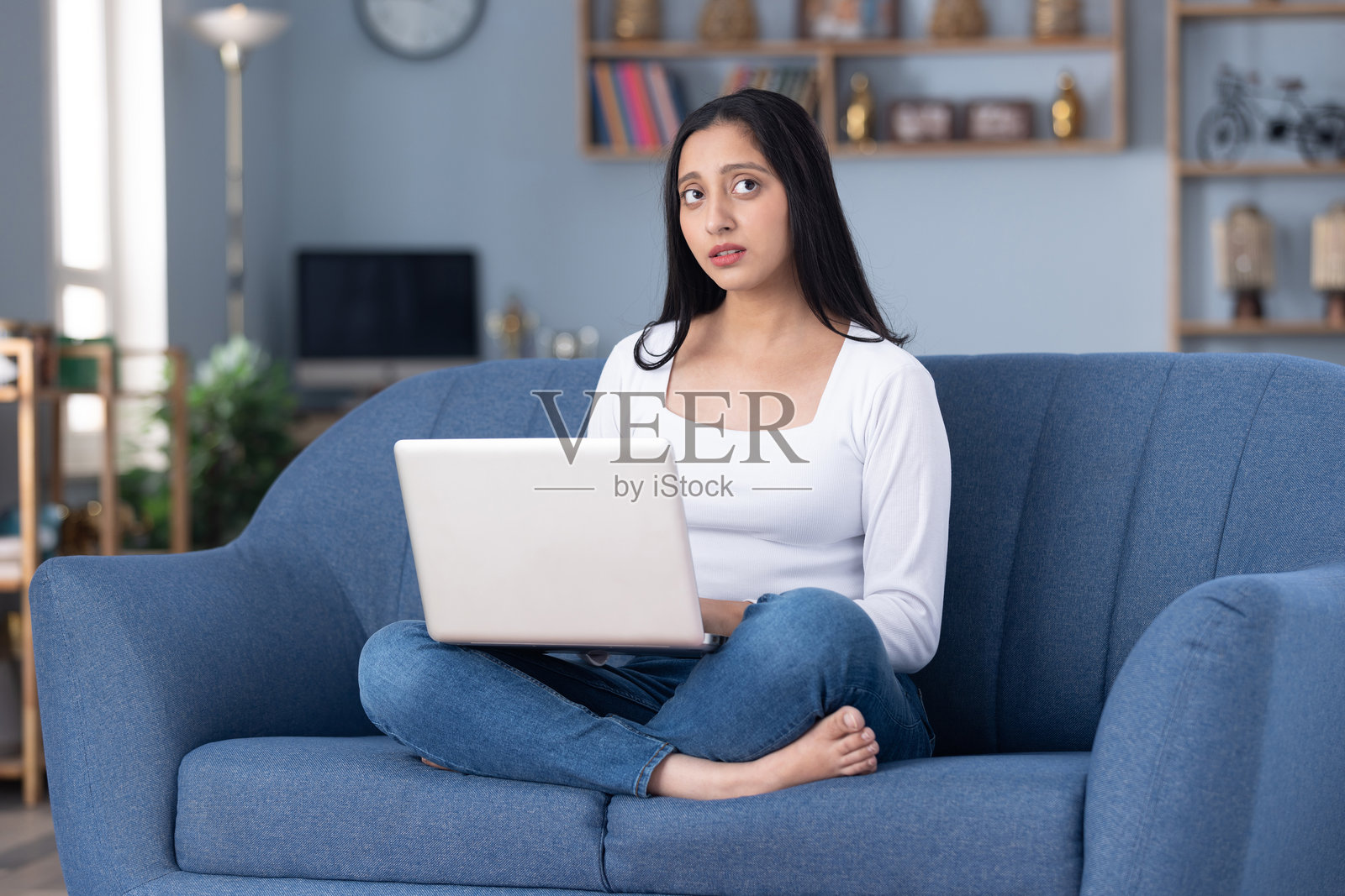 身穿时尚服装的漂亮年轻女孩在家中沙发上使用笔记本电脑的库存照片照片摄影图片