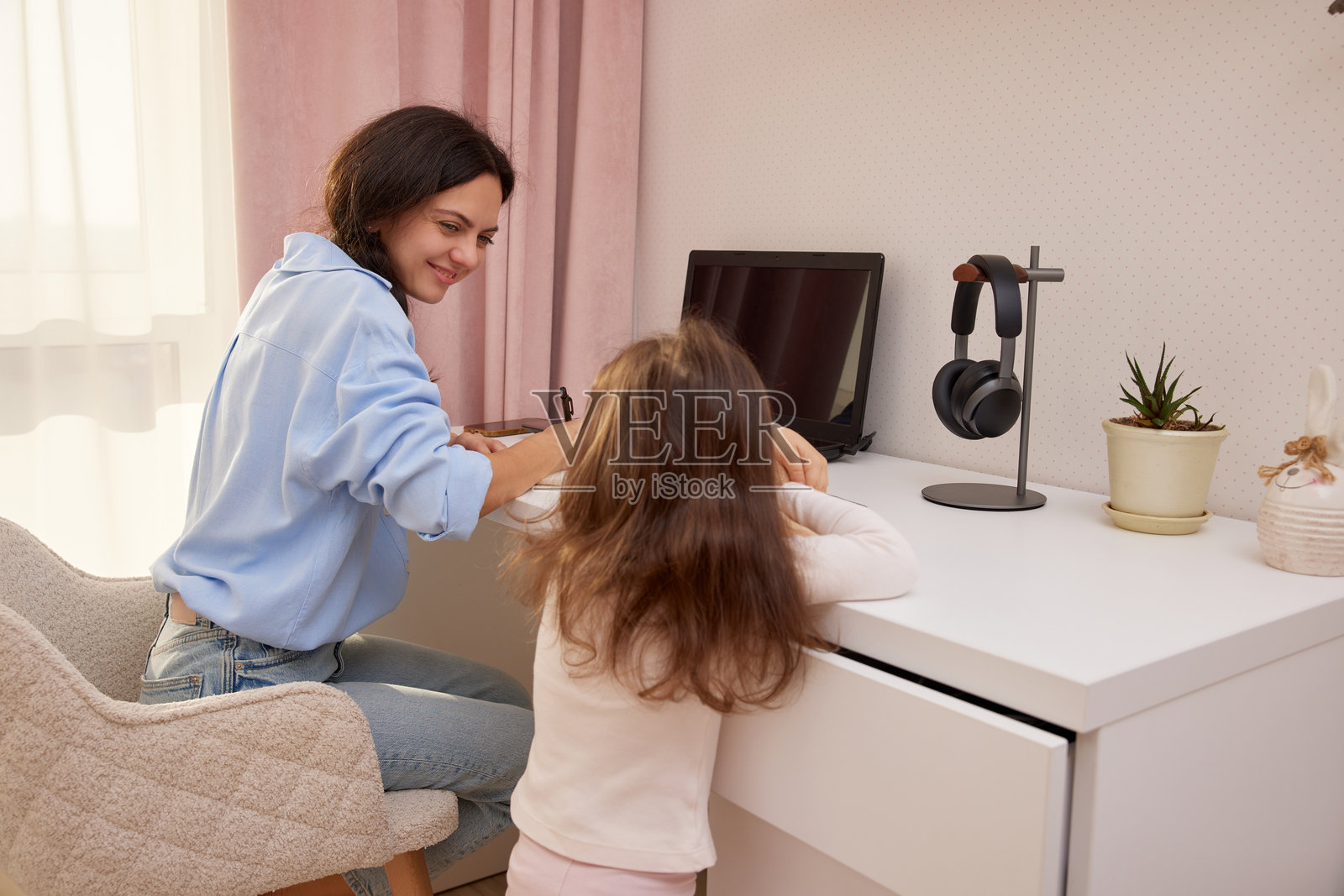 妈妈在家工作，女儿在旁边玩耍照片摄影图片