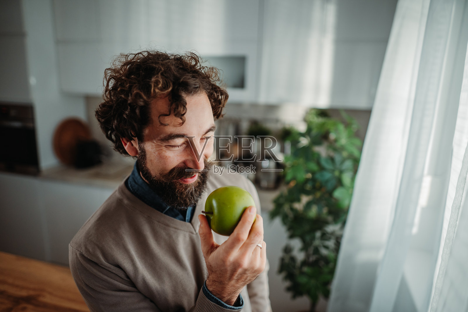 男人在厨房里享用青苹果，健康的零食照片摄影图片