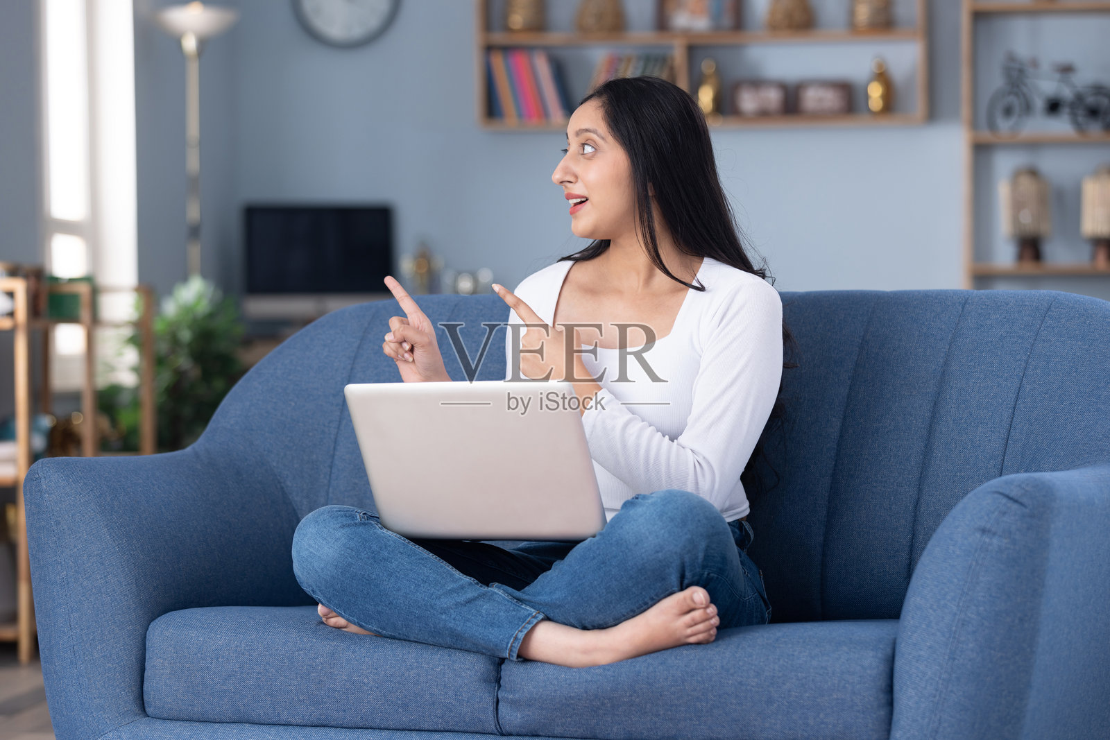 身穿现代服装的漂亮年轻女孩在家中沙发上使用笔记本电脑的图片素材照片摄影图片