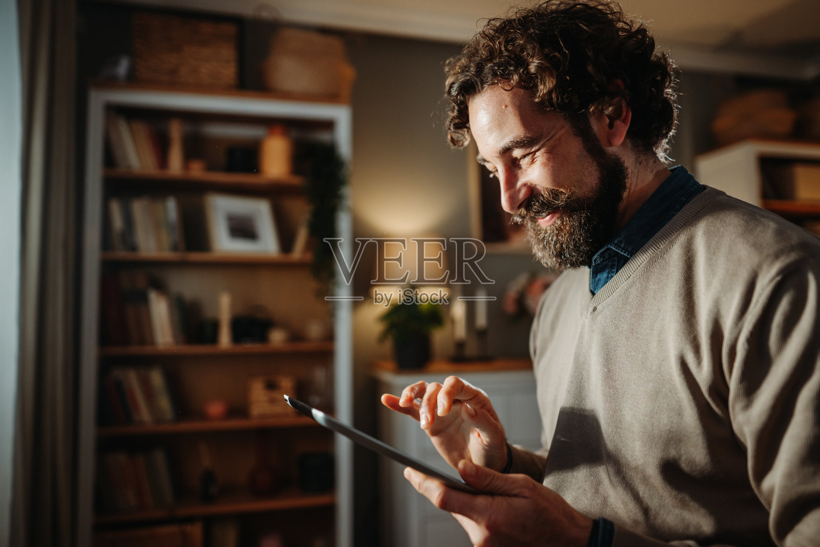 面带微笑的男子在家中使用连接的数码平板电脑照片摄影图片