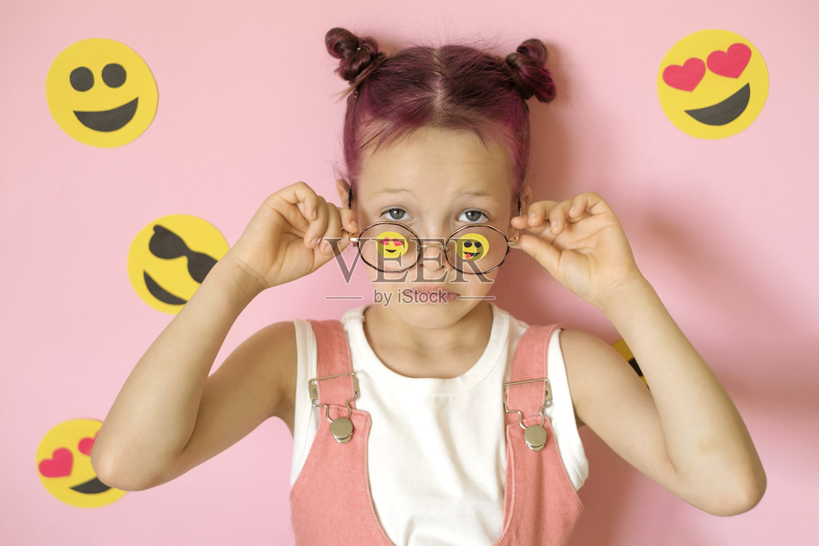 惊讶的孩子摘下眼镜，眼镜上装饰着表情符号和 emoji 图标。世界微笑日照片摄影图片