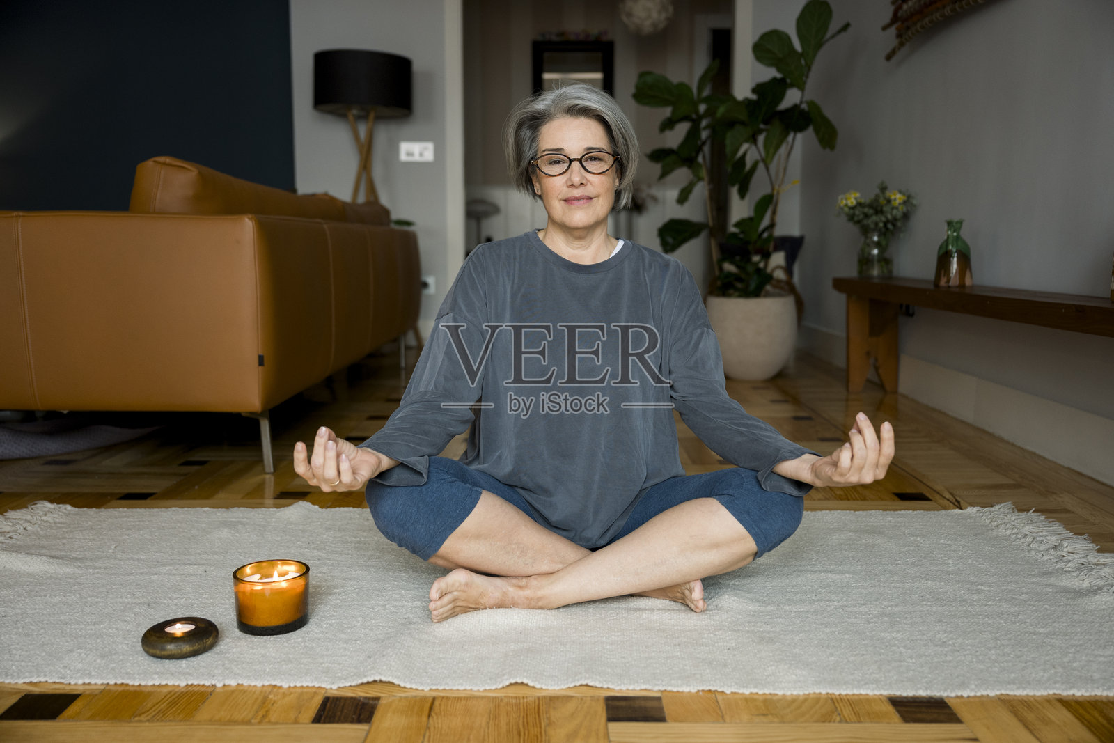 一位年长女性在家中的瑜伽垫上冥想照片摄影图片