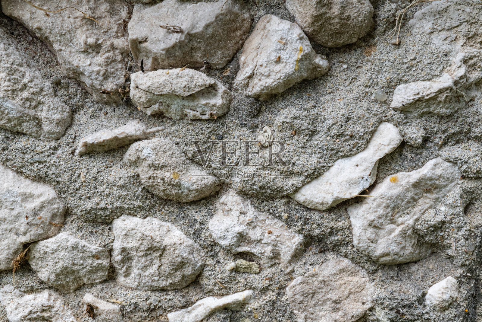 特写镜头：带有不规则纹理和自然色彩变化的质朴石墙照片摄影图片