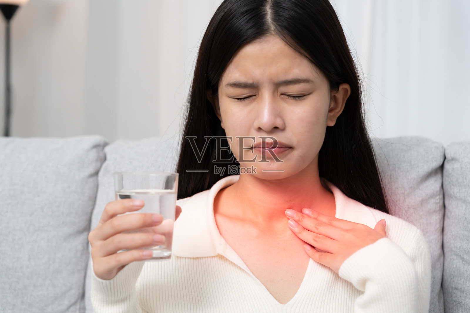 亚洲女性因喉咙痛而捂住脖子。女性扁桃体炎引起炎症。通过饮水、服用抗生素、咨询医生来治疗，病毒，冠状病毒，流感，感冒照片摄影图片