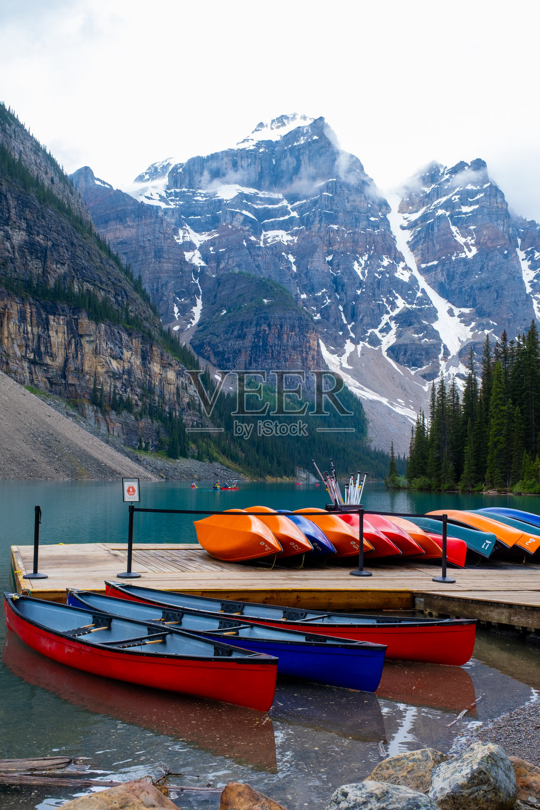 在加拿大班夫，船只停靠在码头，背景是多云天气下的山脉。照片摄影图片