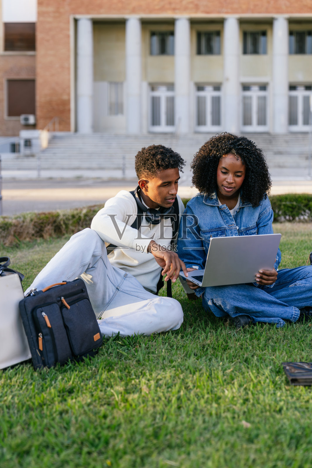不同背景的学生在校园户外合作使用笔记本电脑照片摄影图片