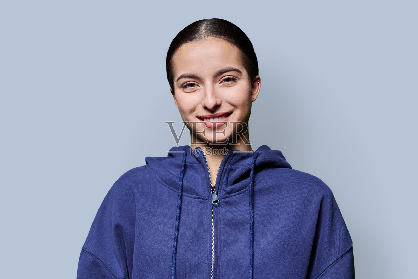 穿着休闲装的年轻美丽女子，在灰色背景下看向镜头照片摄影图片