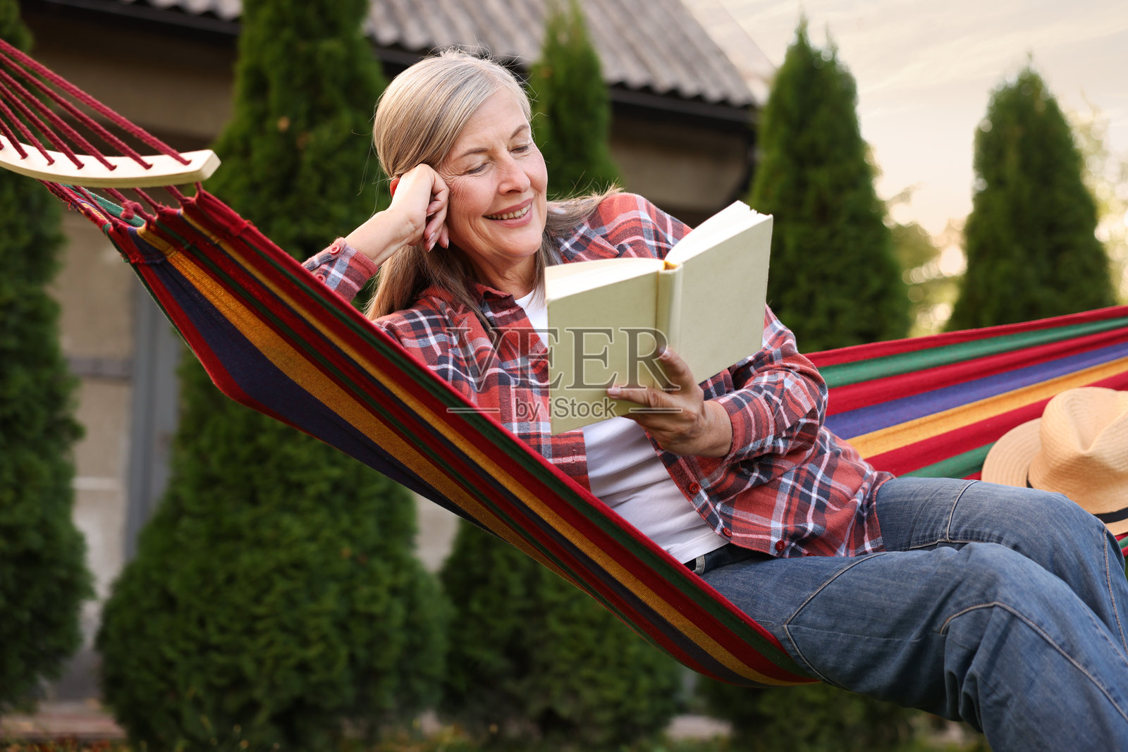 一位年长女士在户外吊床里看书放松照片摄影图片