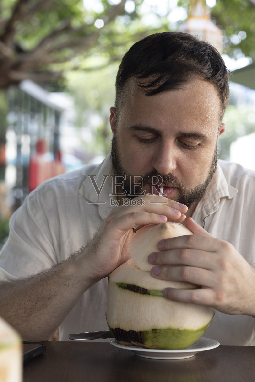 留着胡子的男人在户外享用新鲜椰子饮品照片摄影图片