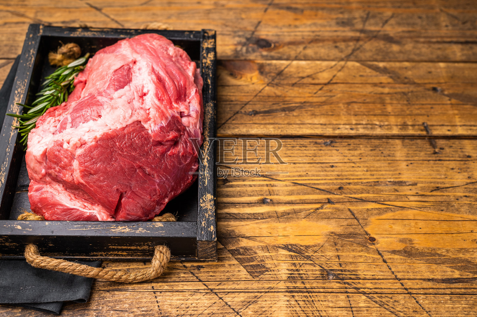 带可见大理石花纹的无骨生牛肉腱子肉，适合炖煮或烤制，是任何美食佳肴或家庭晚餐的美味之选。木质背景。俯视视角。照片摄影图片